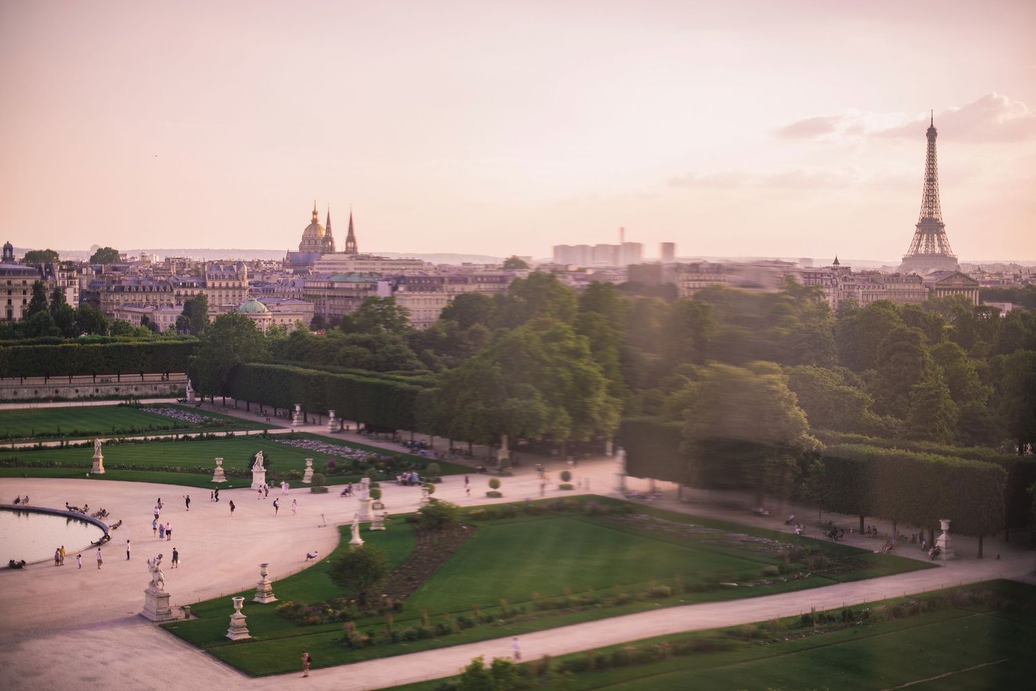 Panoramic sunset view of Paris cityscape with the Eiffel Tower and historic buildings in warm evening light.