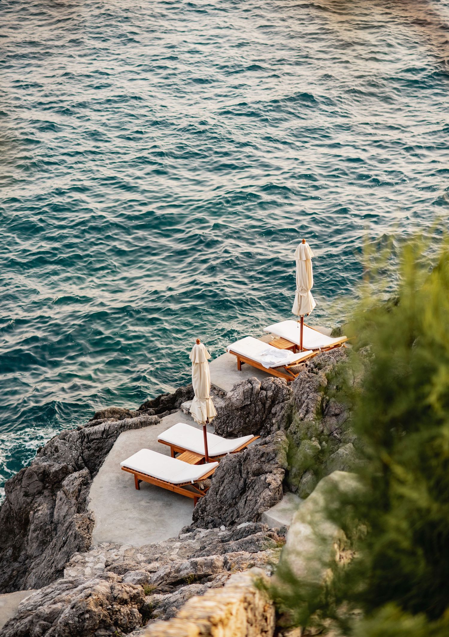 French Riviera wedding in Praiano at Casa Private.  Luxurious seaside sunbeds perched on rocky cliffs above turquoise Mediterranean waters.