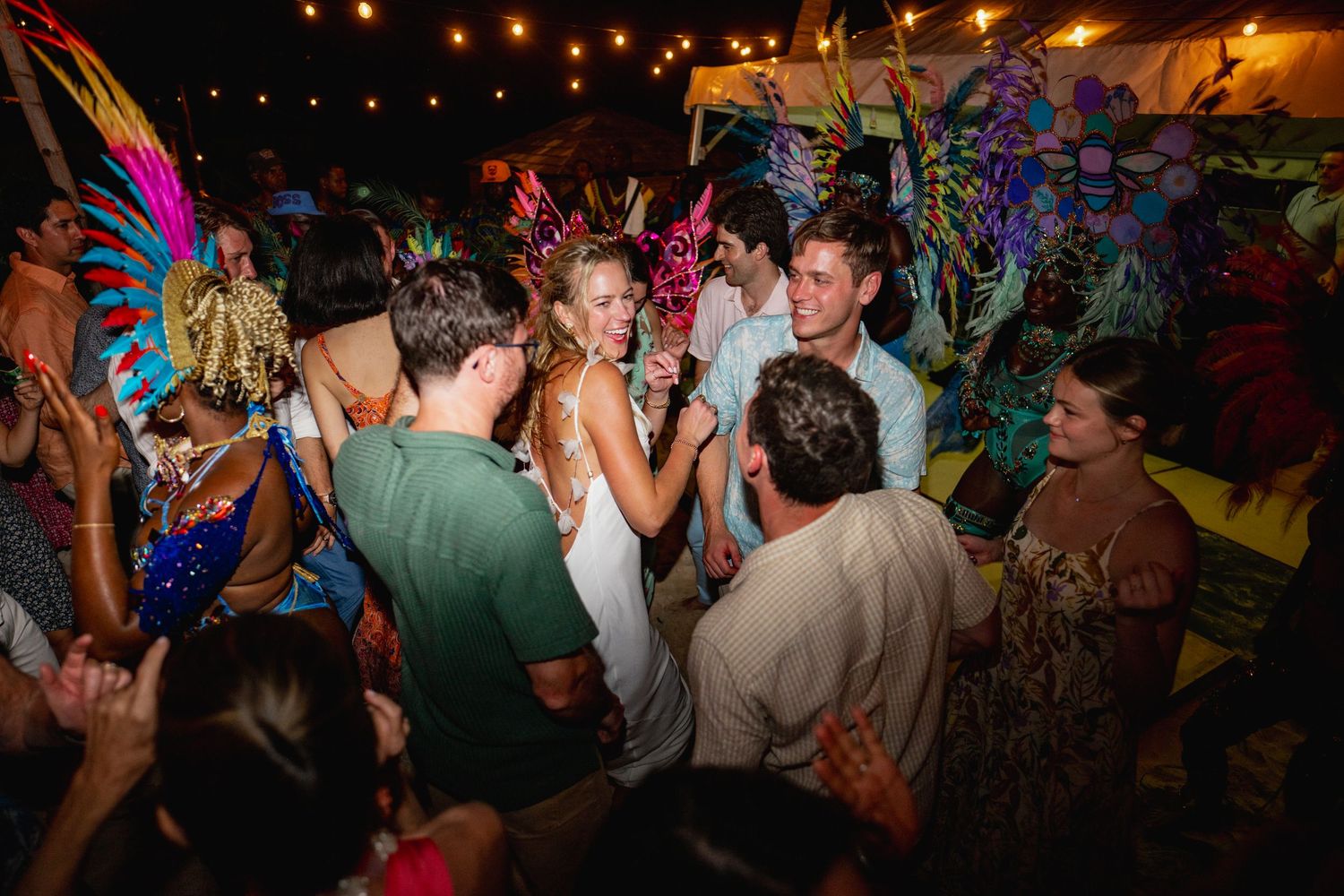 Colorful crowd dancing at a nightclub party with vibrant fairy wing costumes and festive lighting.