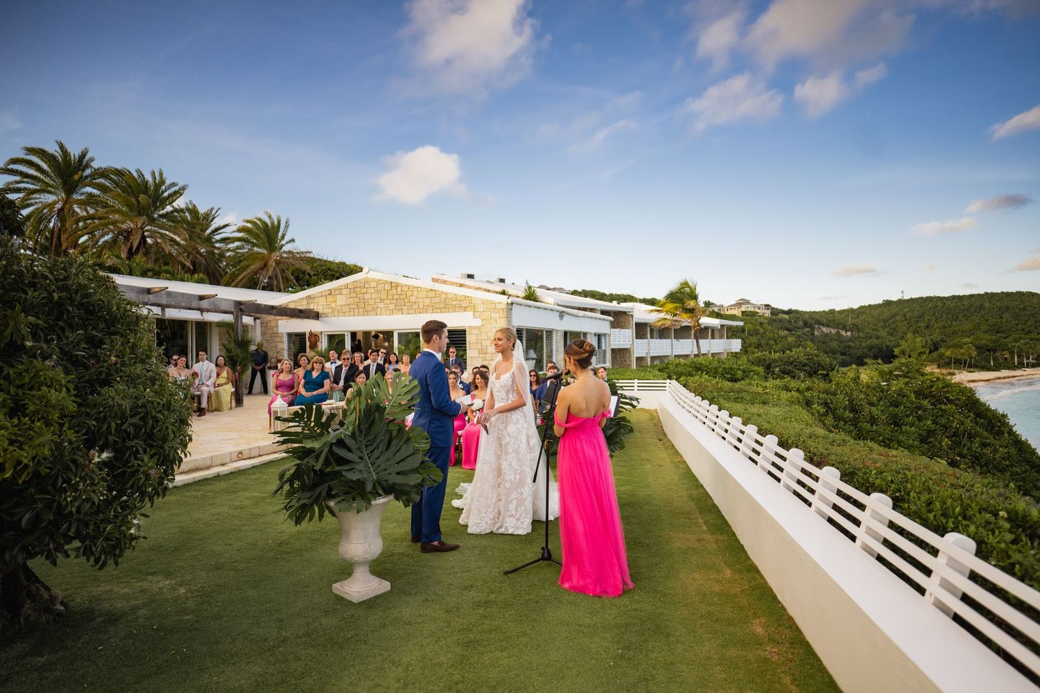 Wedding guests gather on scenic tropical terrace overlooking ocean view.