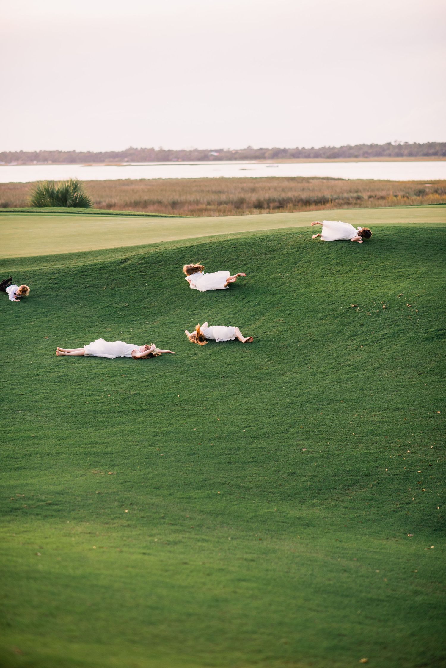 Three photos of a person lying down on a grassy hill slope against a distant horizon on a golf course.