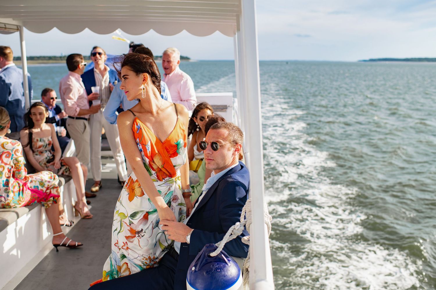 People enjoying a boat ride on the water during a sunny day with waves splashing behind the vessel.
