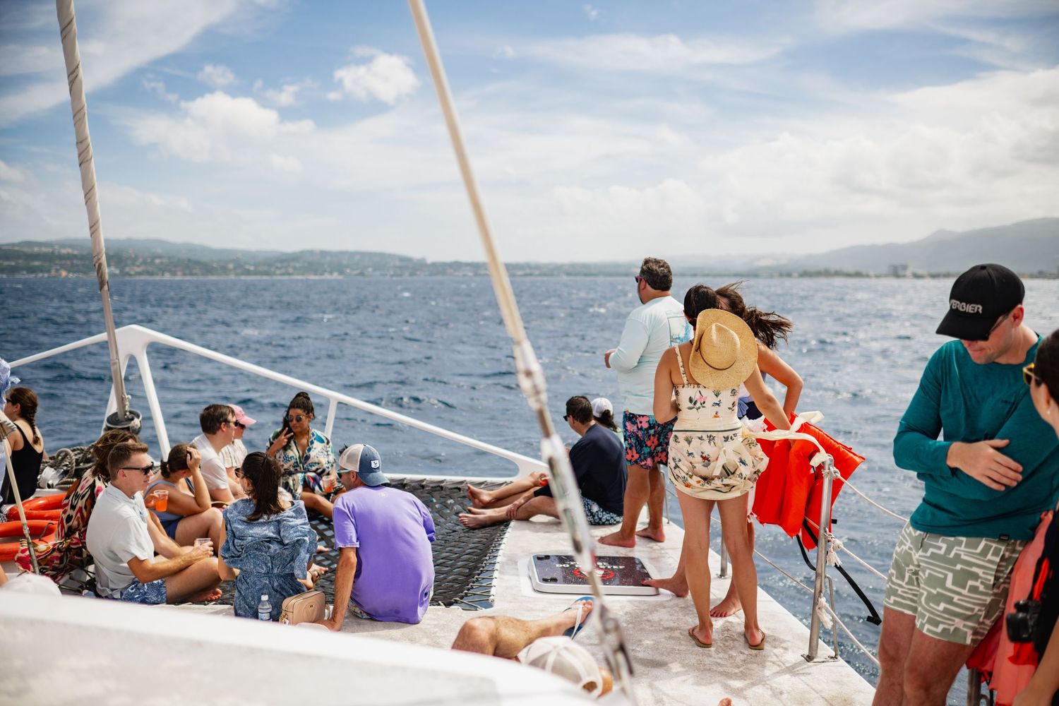 People enjoying a boat tour on a sunny day with scenic ocean and mountain views in the background.