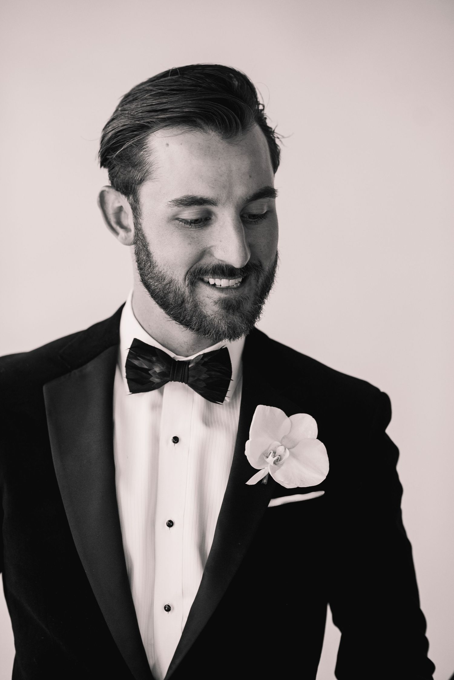 A series of black and white portraits showing details of a groom in classic tuxedo with bowtie and boutonniere.
