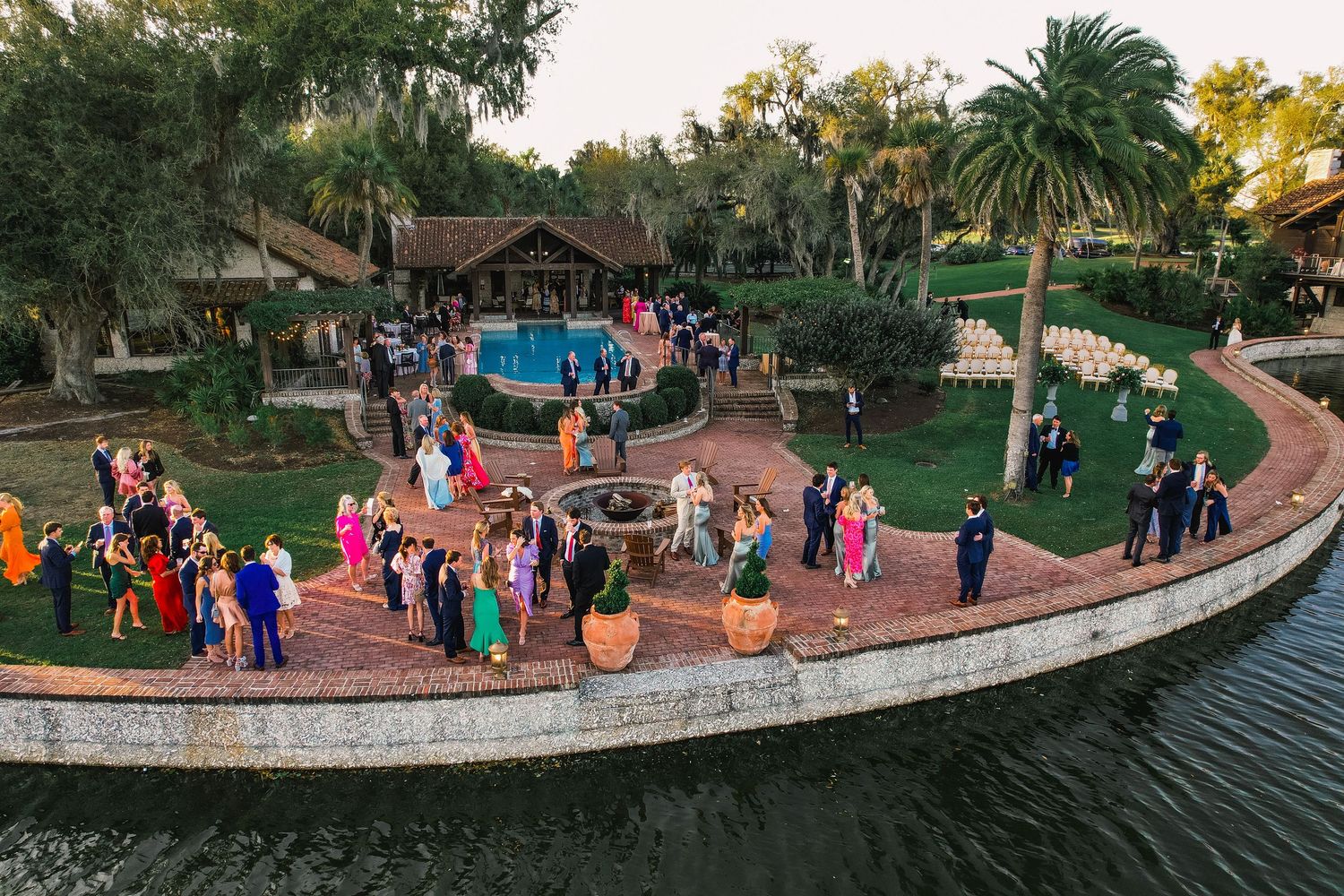 Panoramic view of families gathering at a park with Halloween pumpkin decorations along a curved stone wall at dusk.