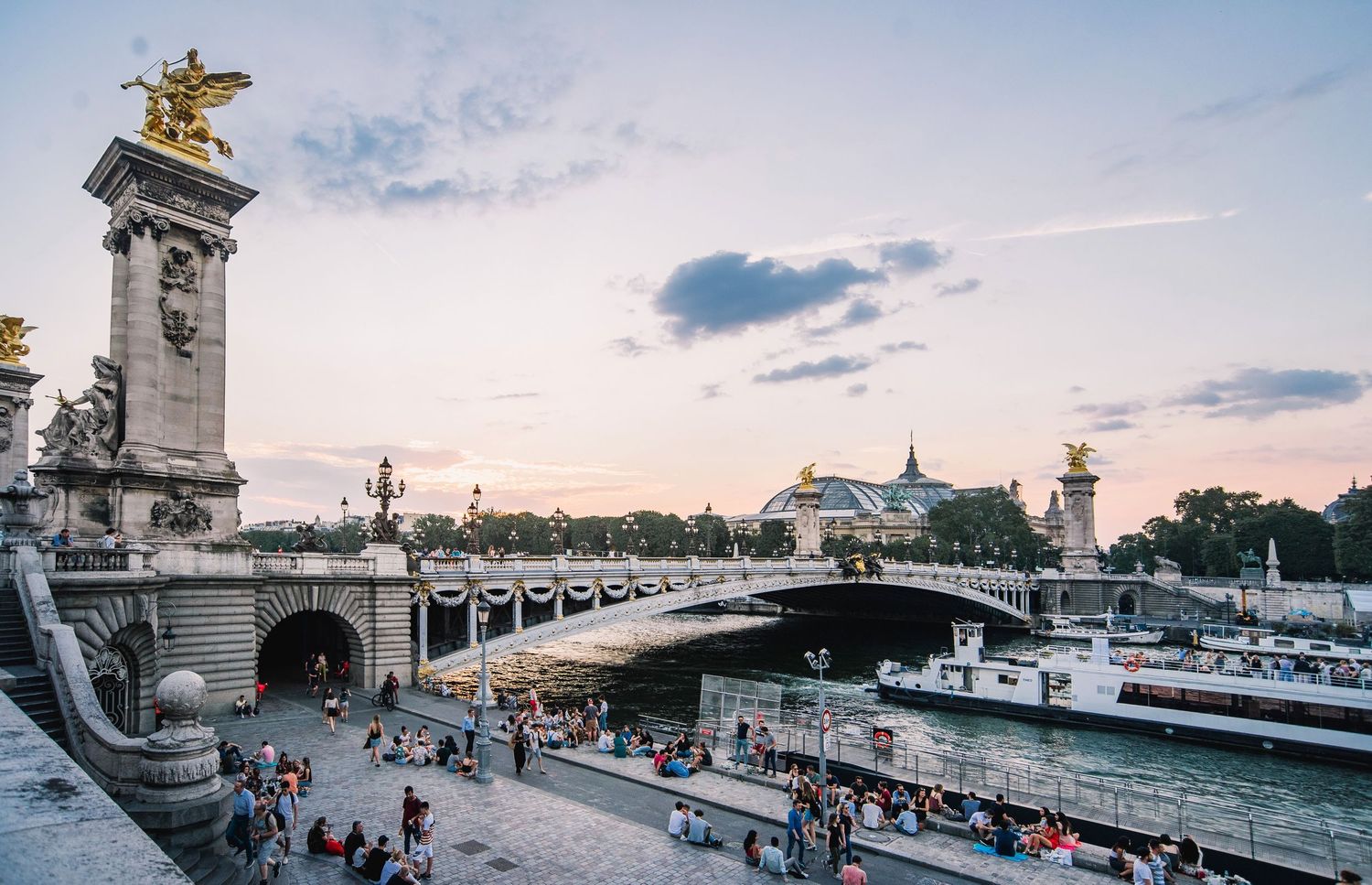 Panoramic view of Pont Alexandre III bridge in Paris with ornate details at sunset.