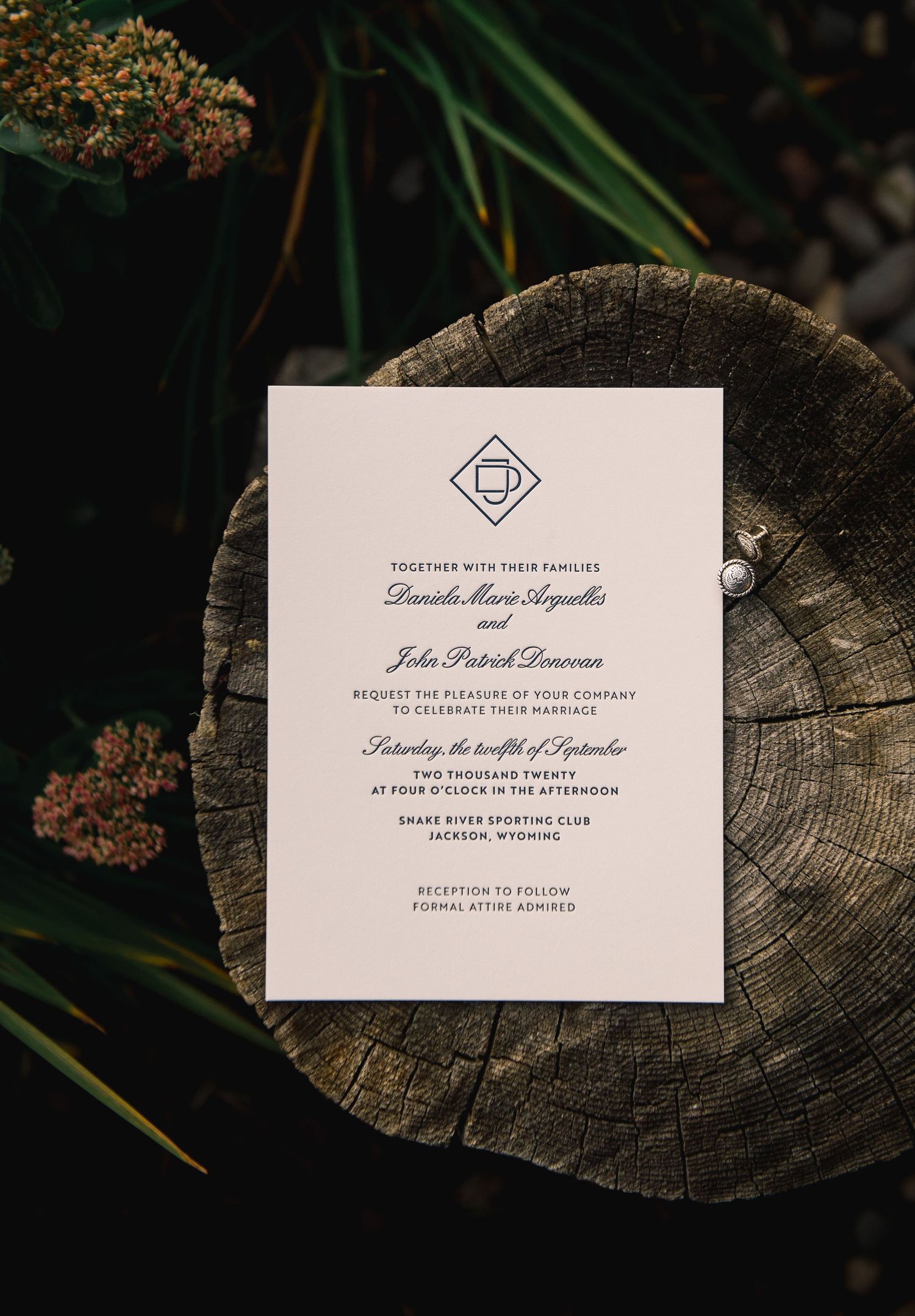 Wedding invitation suite with elegant white cards displayed on rustic wood surfaces in natural outdoor lighting.