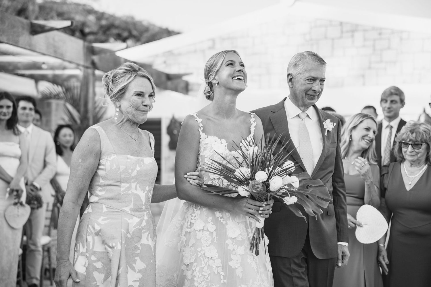 Black and white photos of wedding guests mingling and celebrating at an outdoor reception.