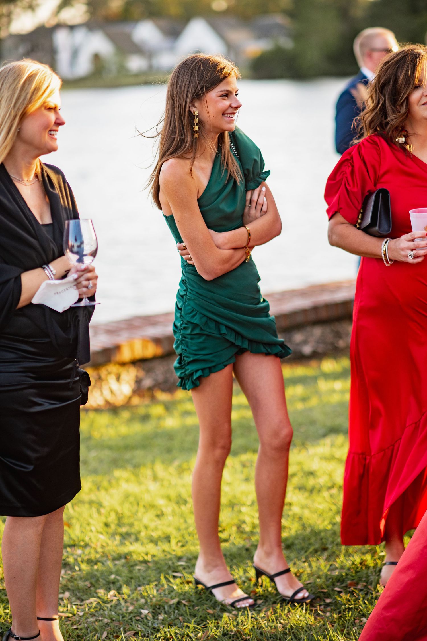 A row of people in formal attire stand outdoors on grass, showing only their lower bodies from waist down.