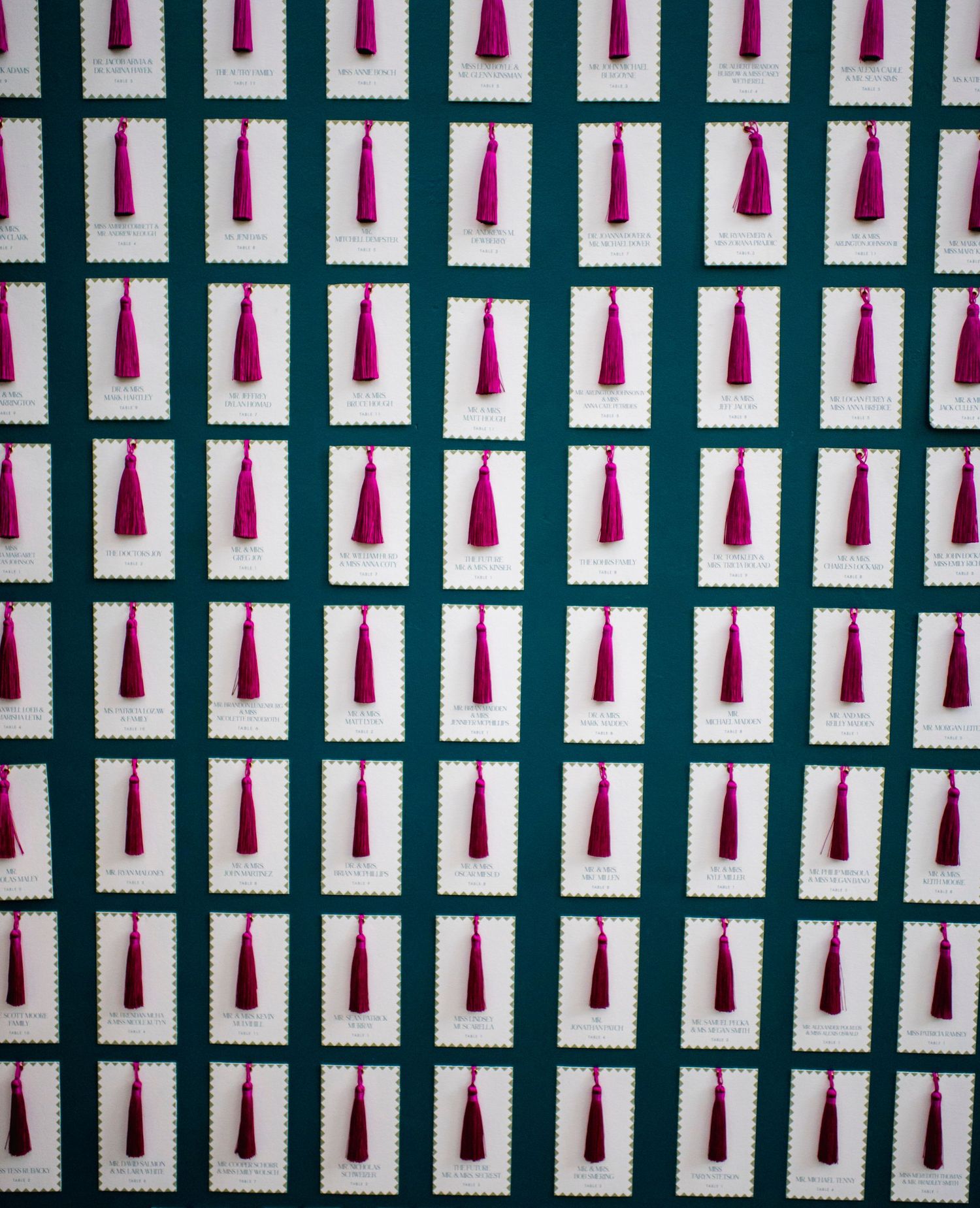 Rows of pink and red wine bottles arranged in a geometric pattern against a dark background.