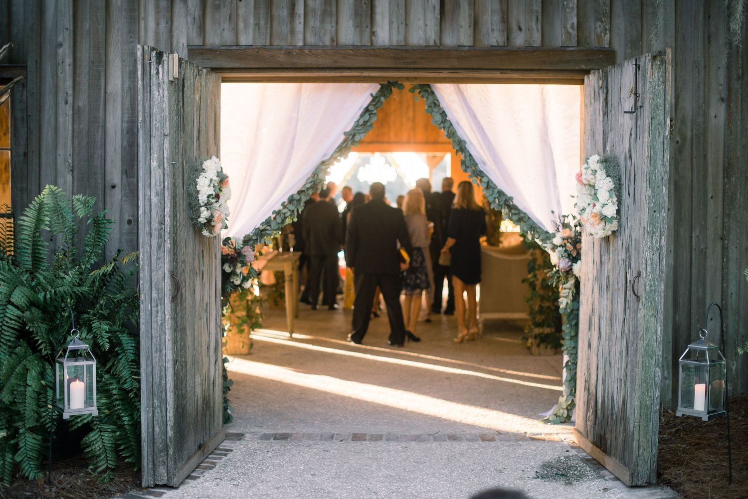 Wooden archway entrance decorated with string lights creating a rustic outdoor wedding venue.