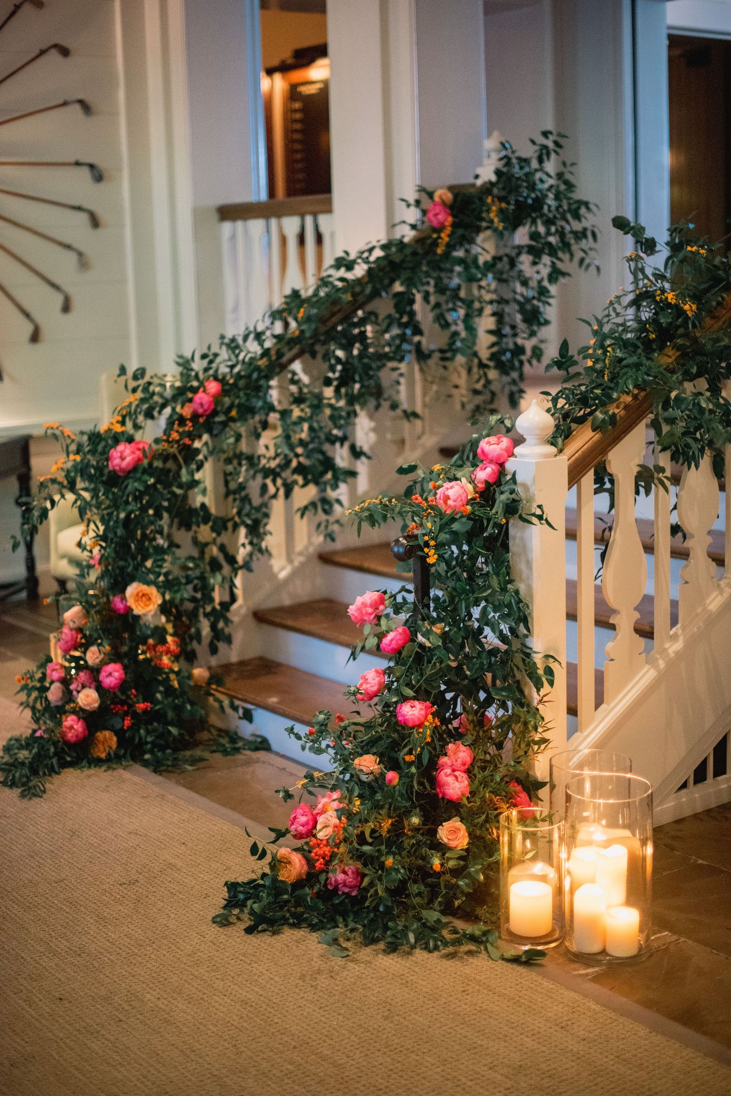 Romantic staircase decorated with lush greenery, pink roses, and glowing lanterns creating an elegant wedding atmosphere.