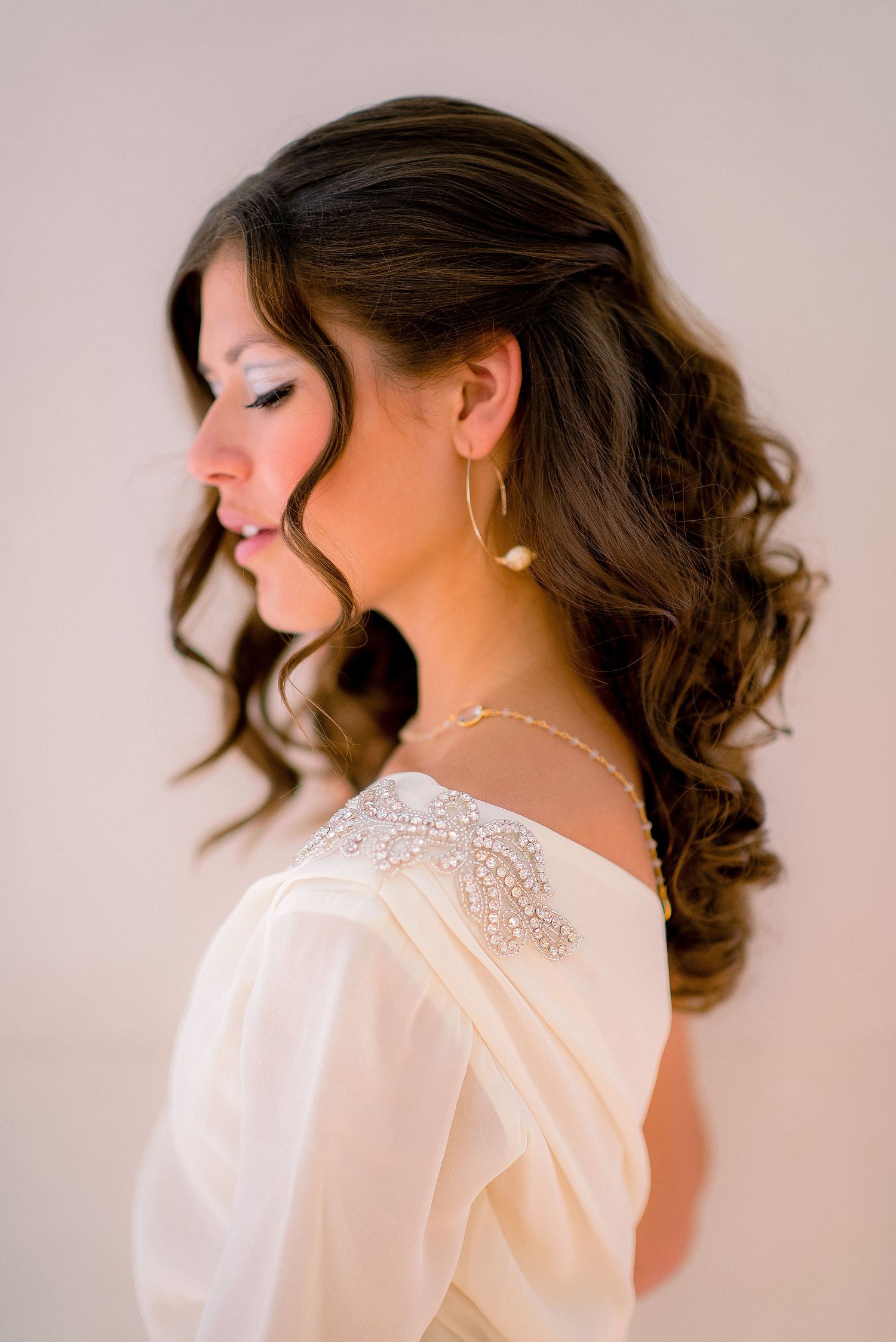 Elegant bridal portrait series showing romantic updo hairstyle and delicate pearl jewelry against neutral backdrop.