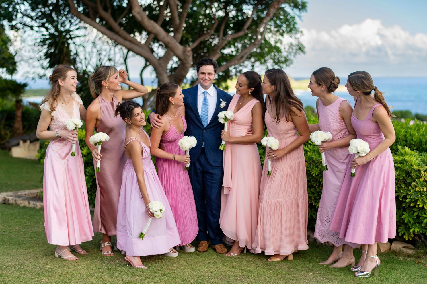 Wedding party wearing pink bridesmaid dresses posing together outdoors.