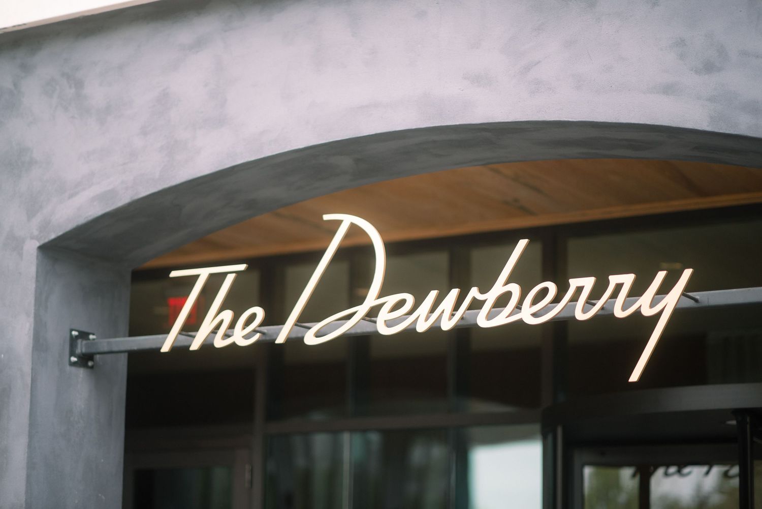 Illuminated storefront sign reading 'The Dewberry' glows against a dark exterior wall.
