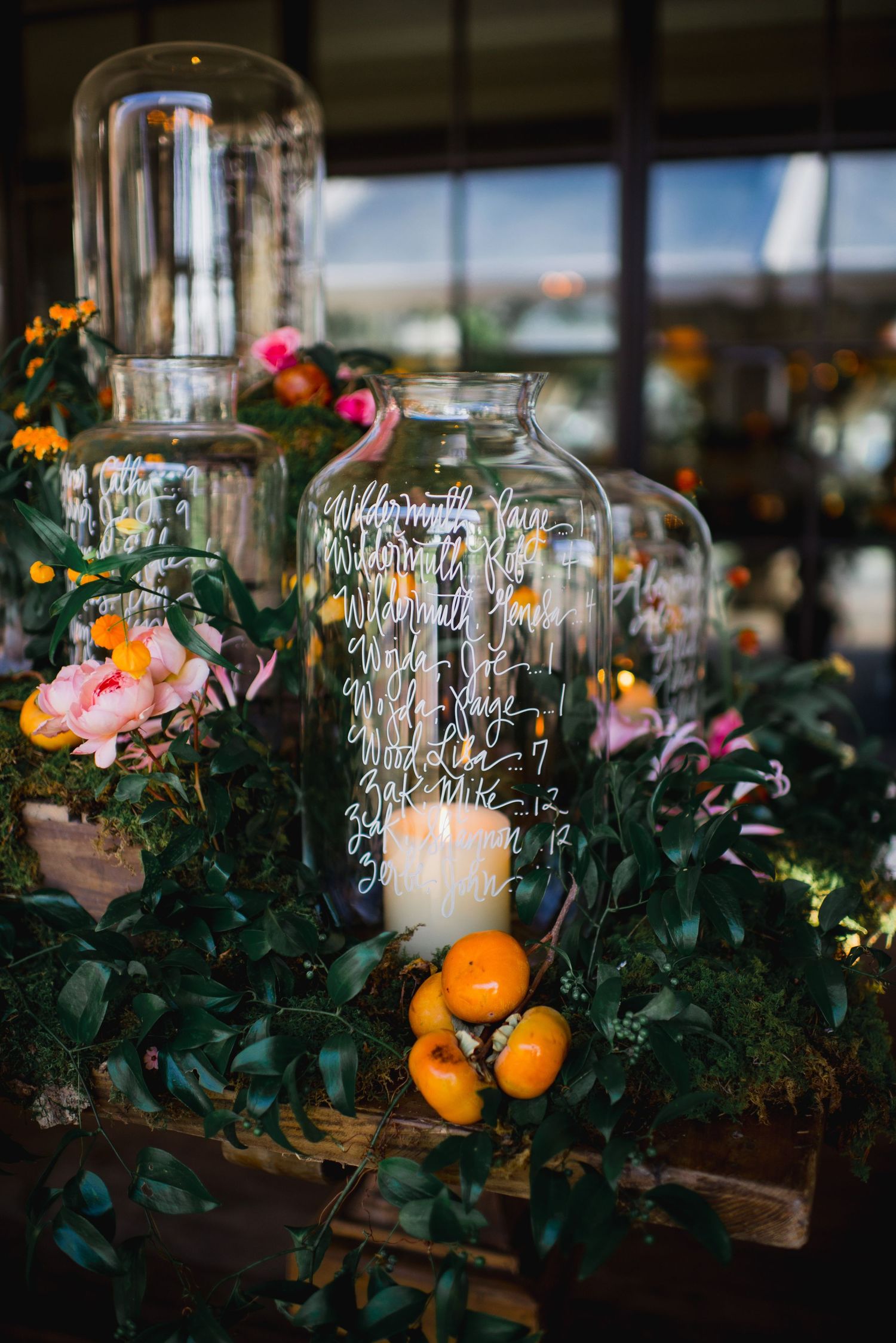 Glass candle holders with citrus fruits and floral arrangements create a romantic rustic table centerpiece.