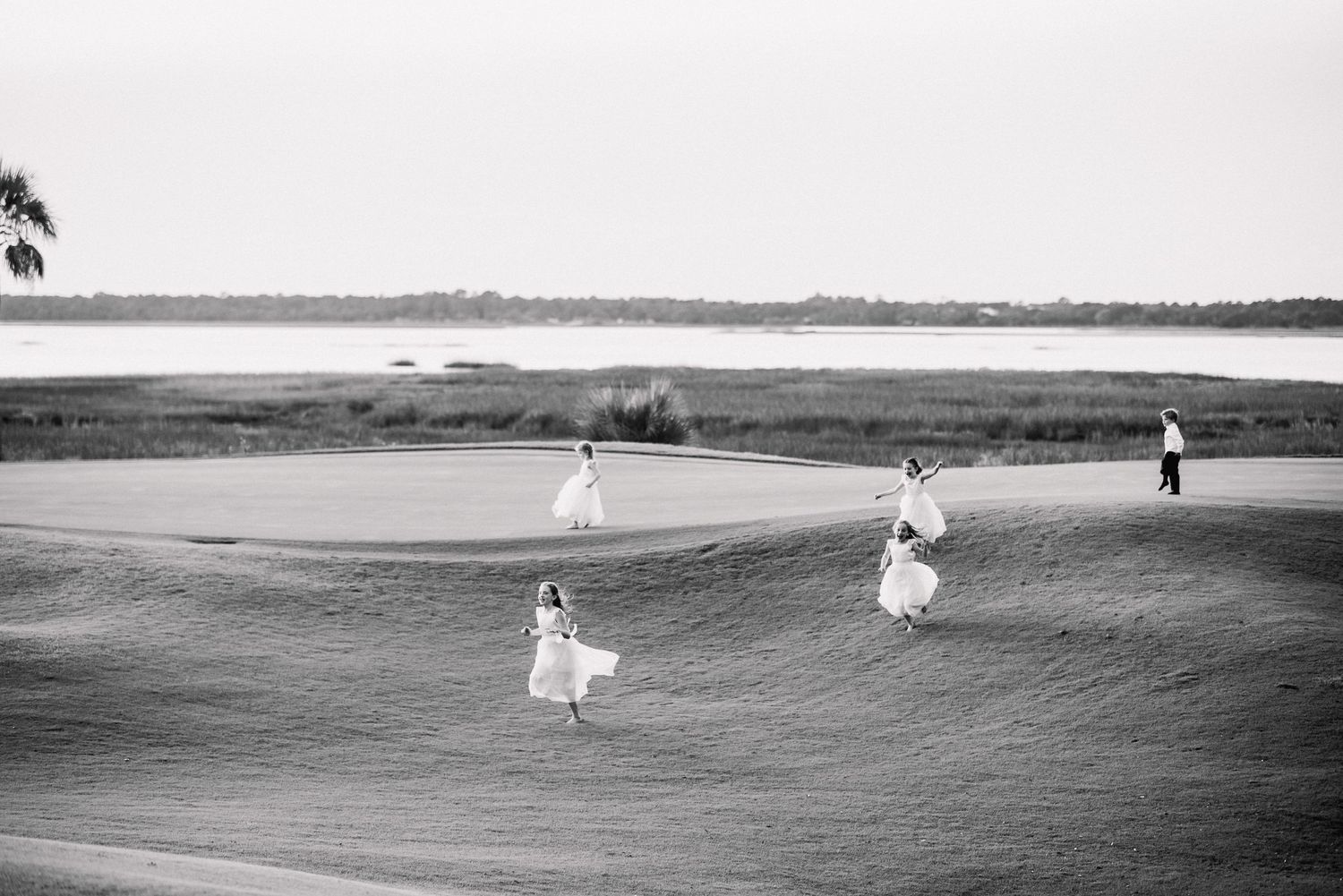 A sequence of black and white photographs showing a figure walking along a vast beach landscape with a flowing dress.