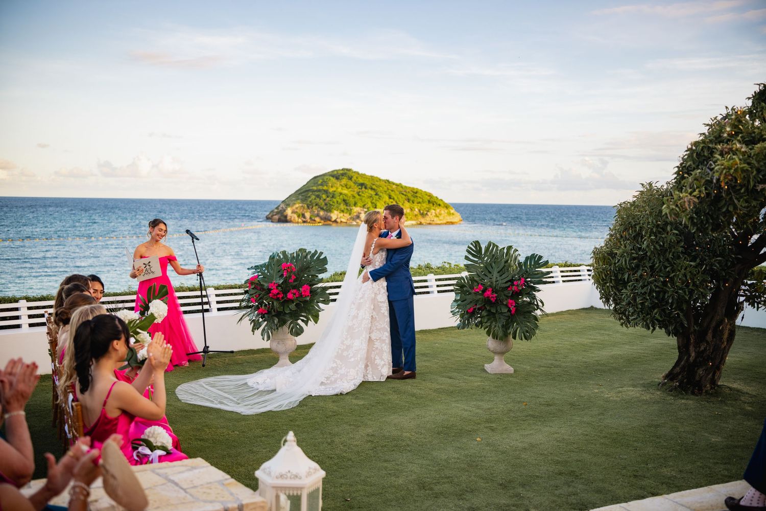 Scenic beach wedding venue with white fence, tropical flowers and ocean view.