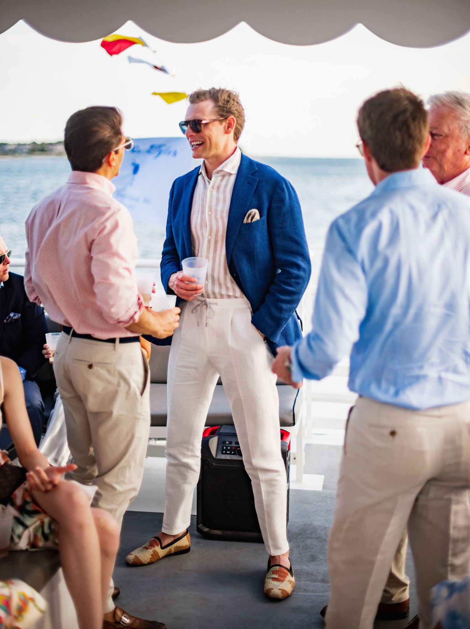 Wedding guests in summer attire gather on a dock for a nautical celebration.