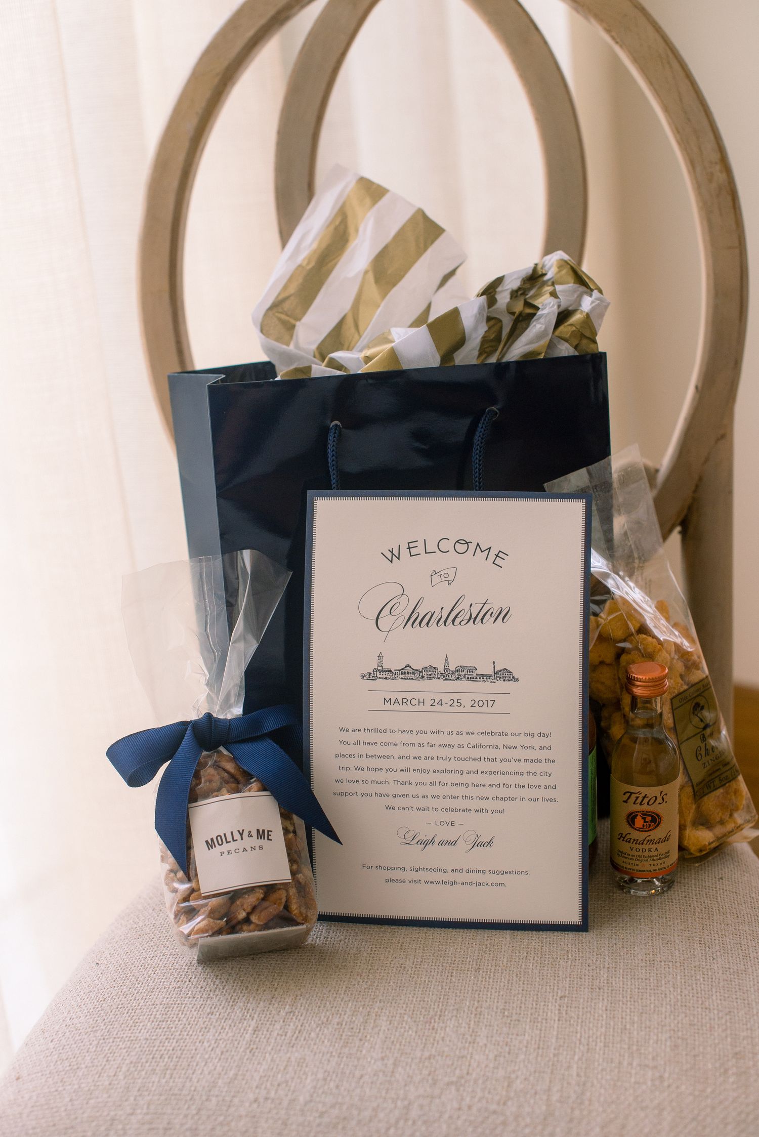 Wedding welcome bags with navy blue accents display cards and treats arranged on a white textured surface.