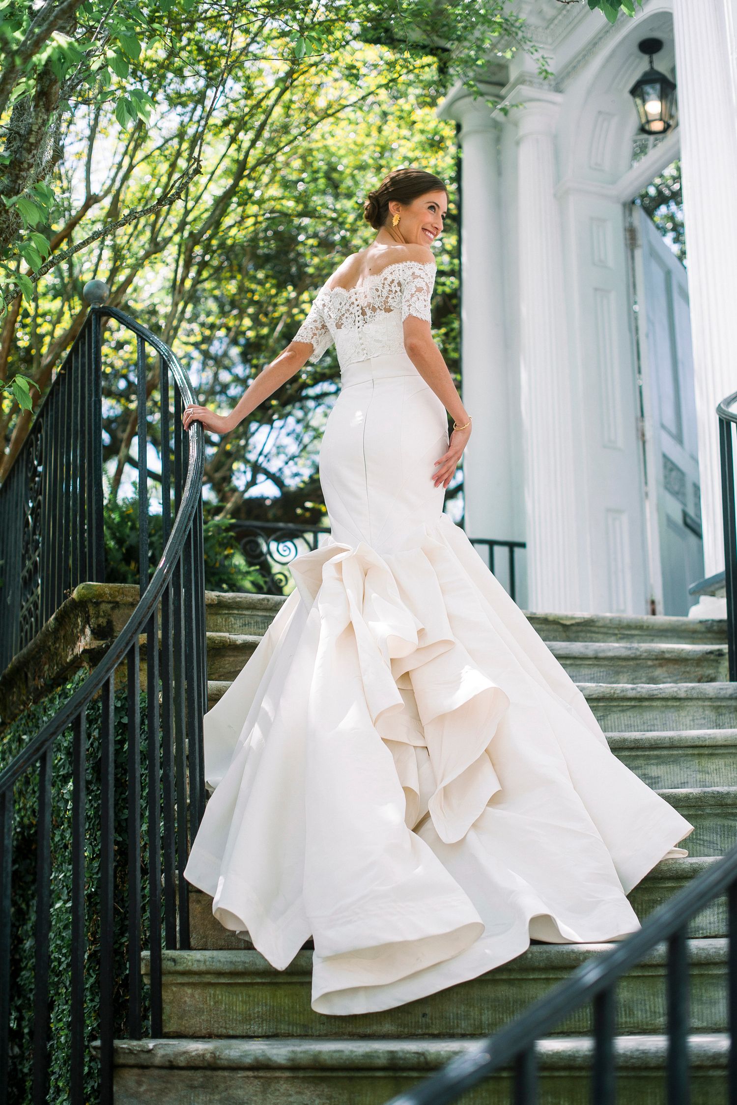 Wedding dress with flowing ruffles captured on white columned staircase.