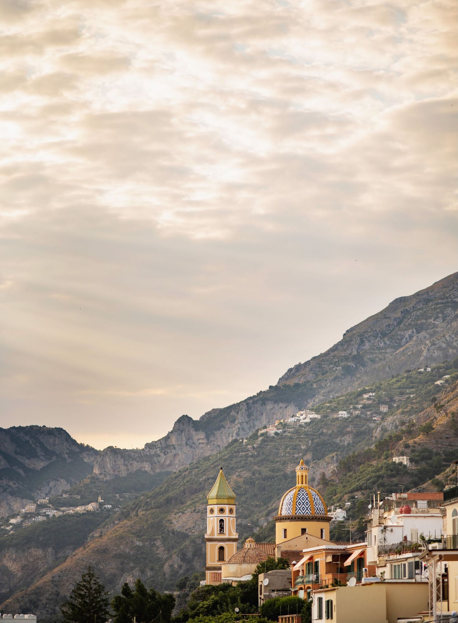 Scenic coastal town of Praiano, Italy nestled in mountains with church steeples and traditional architecture along the Mediterranean.