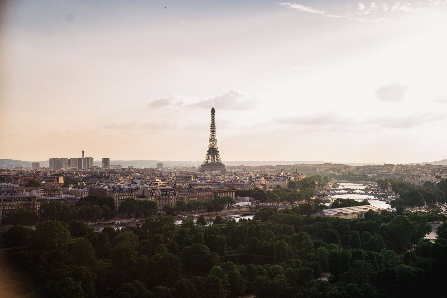 Panoramic cityscape of Paris at sunset showing the iconic Eiffel Tower and urban sprawl.