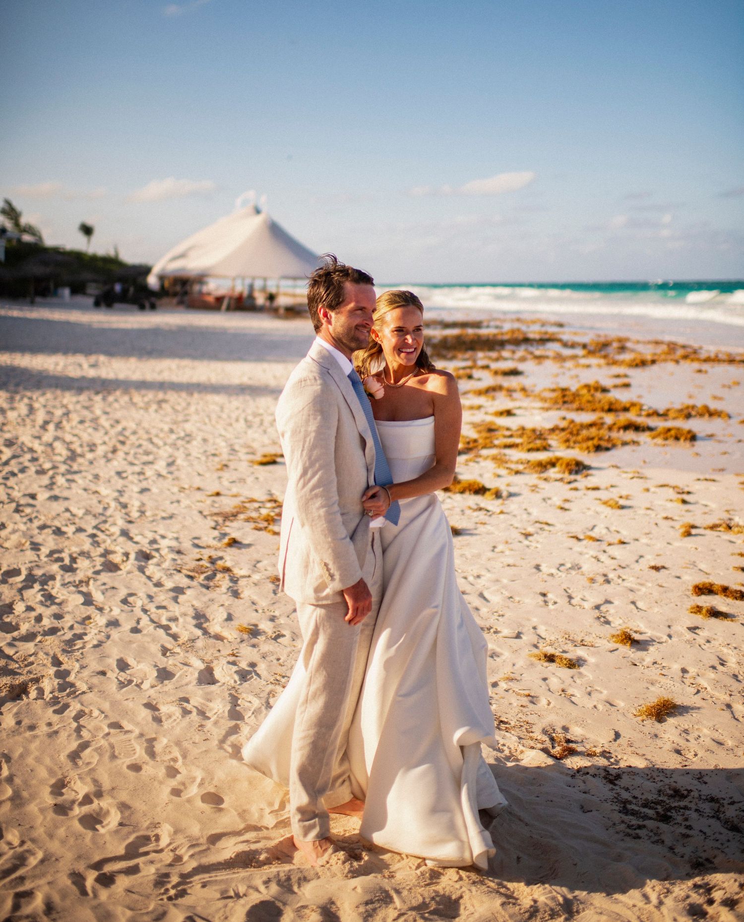 Newlyweds sharing an intimate moment on a sandy beach with a white tent in the background on Bahamas beach
