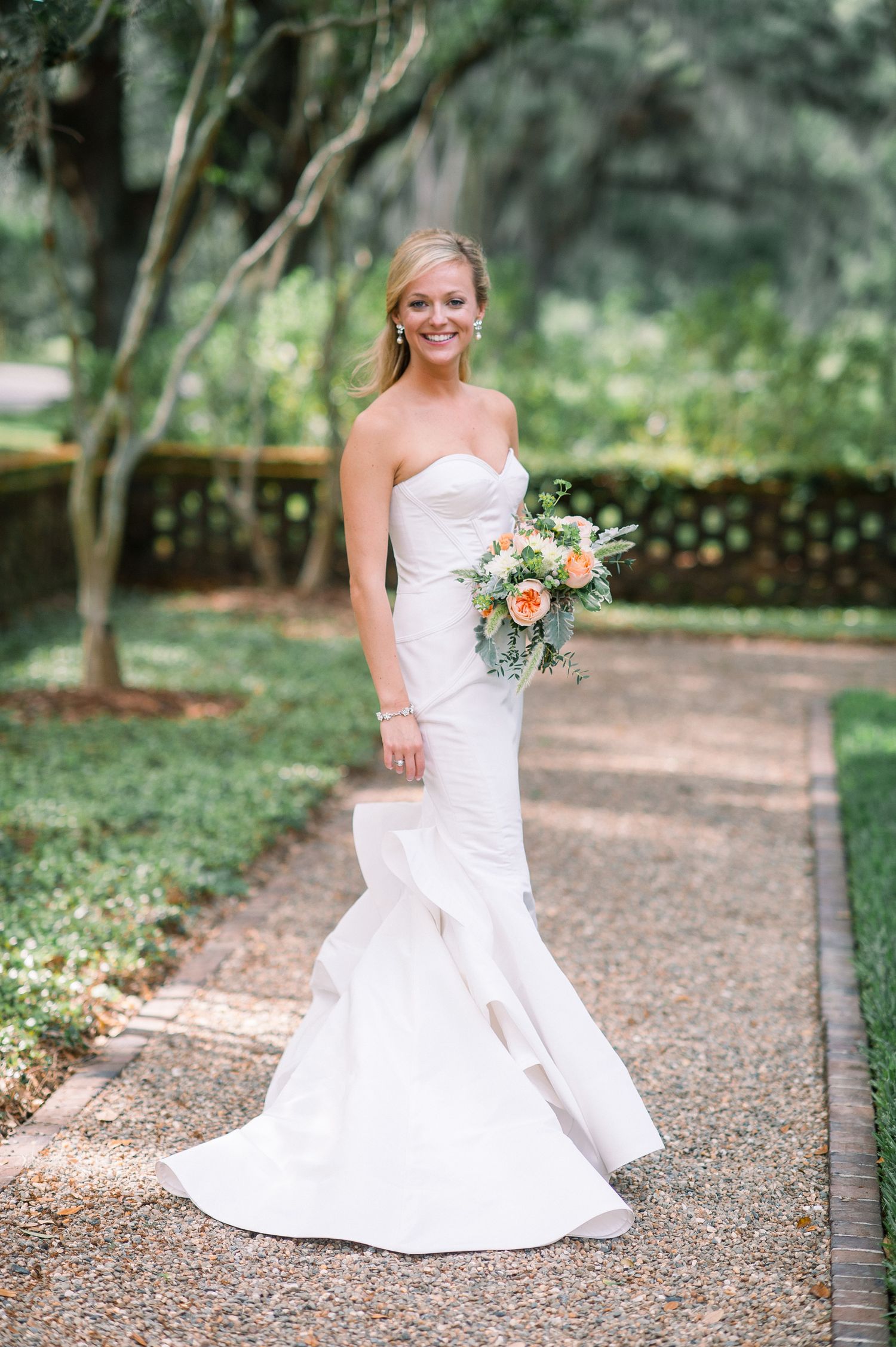 A bridal portrait series showing a white wedding gown against a lush garden path backdrop with peach floral bouquet.