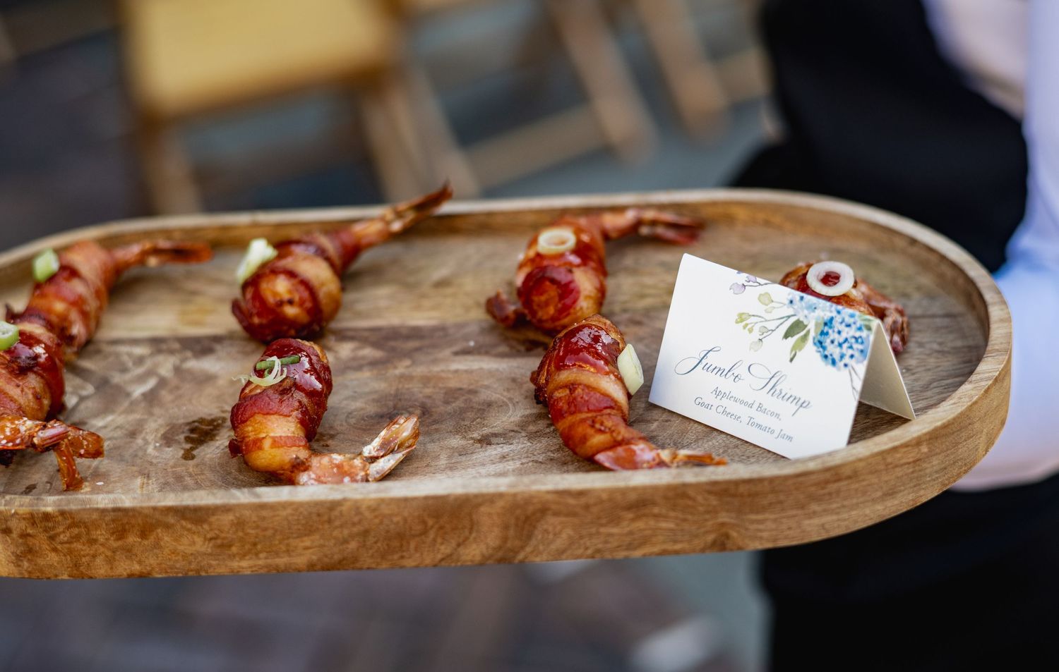 A rustic wooden serving board displays colorful cherry tomatoes and other ingredients in a restaurant setting.
