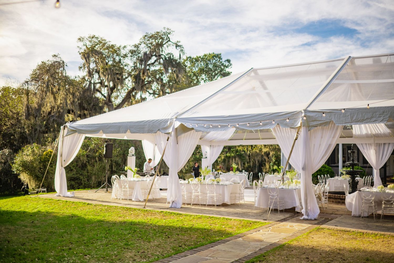 Elegant white tent pavilions set up for an outdoor event with draping fabric and scenic natural surroundings.