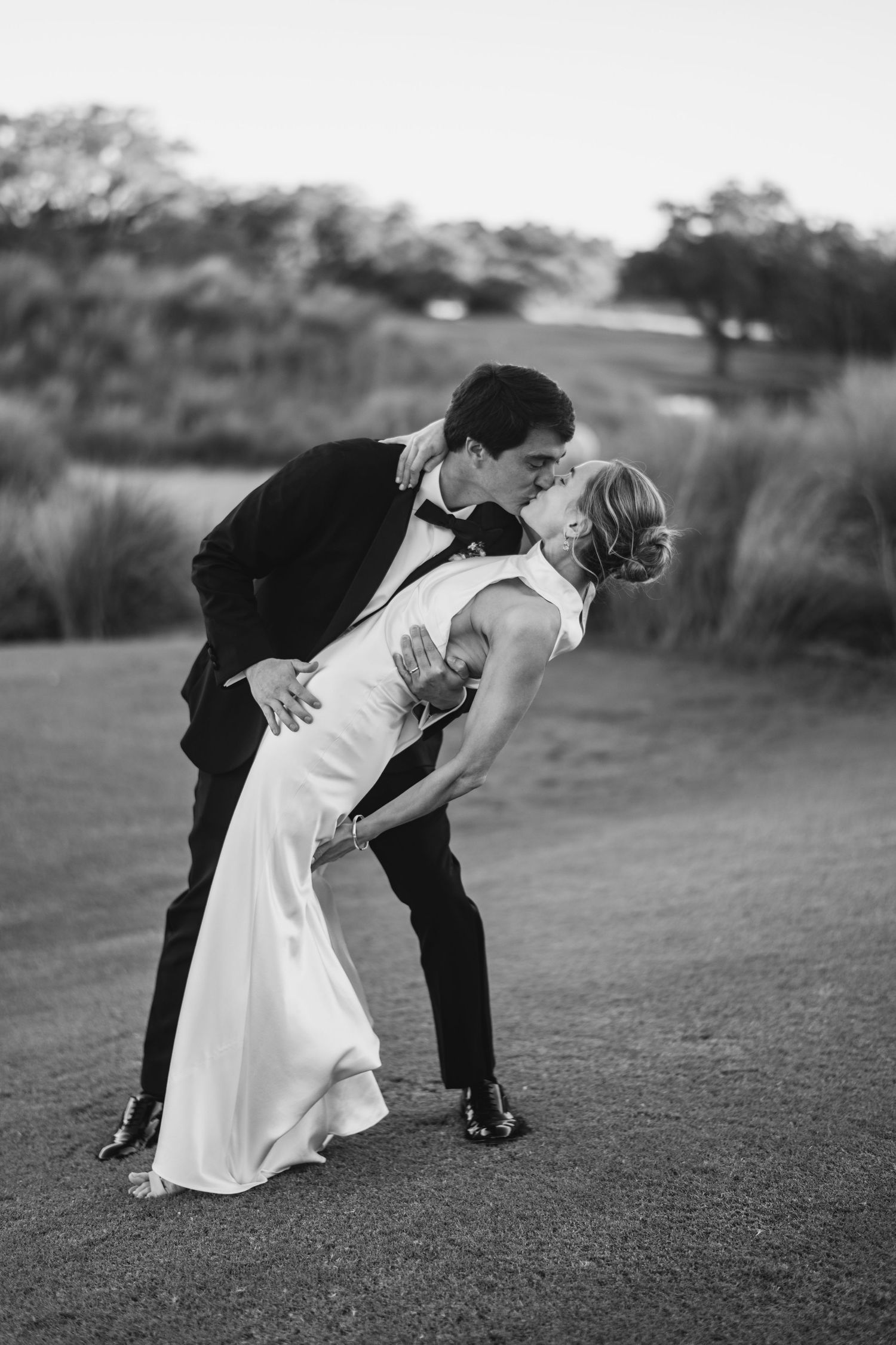 A romantic black and white wedding photo sequence shows a couple in formal attire sharing a playful dip kiss on a grassy field.