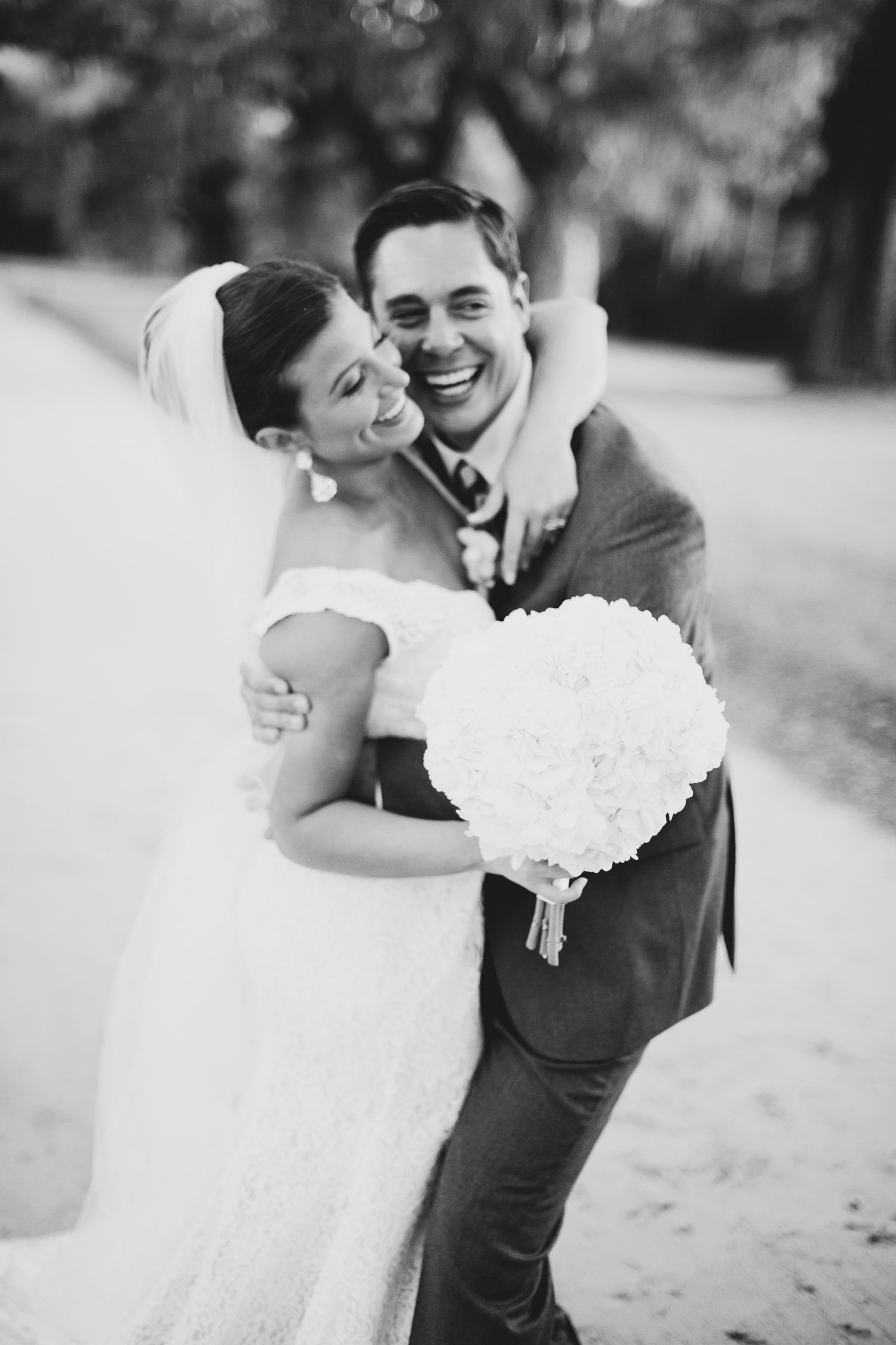 A black and white wedding portrait capturing a joyful embrace.