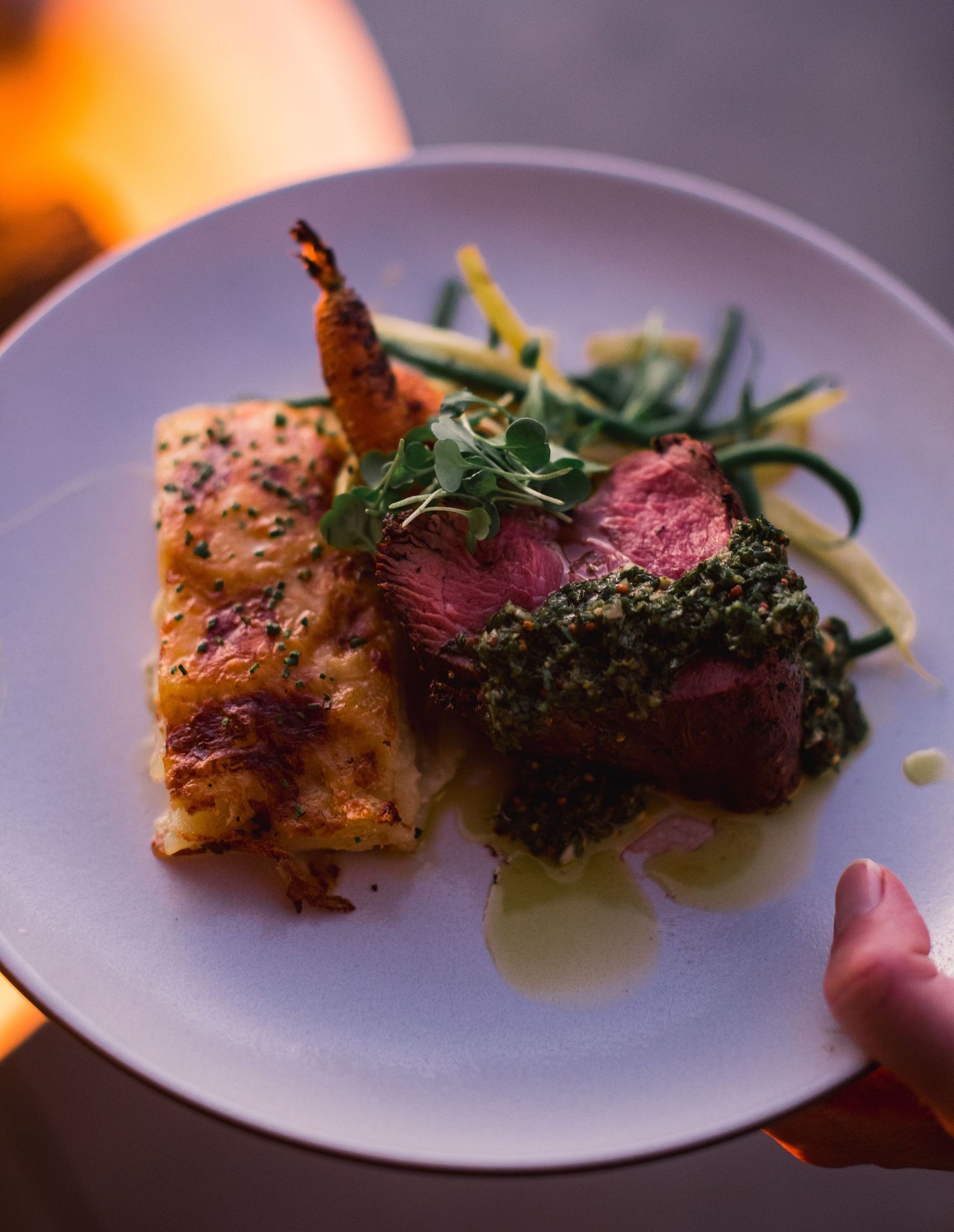 A series of plated dishes featuring grilled meat and vegetables artfully presented on white plates.