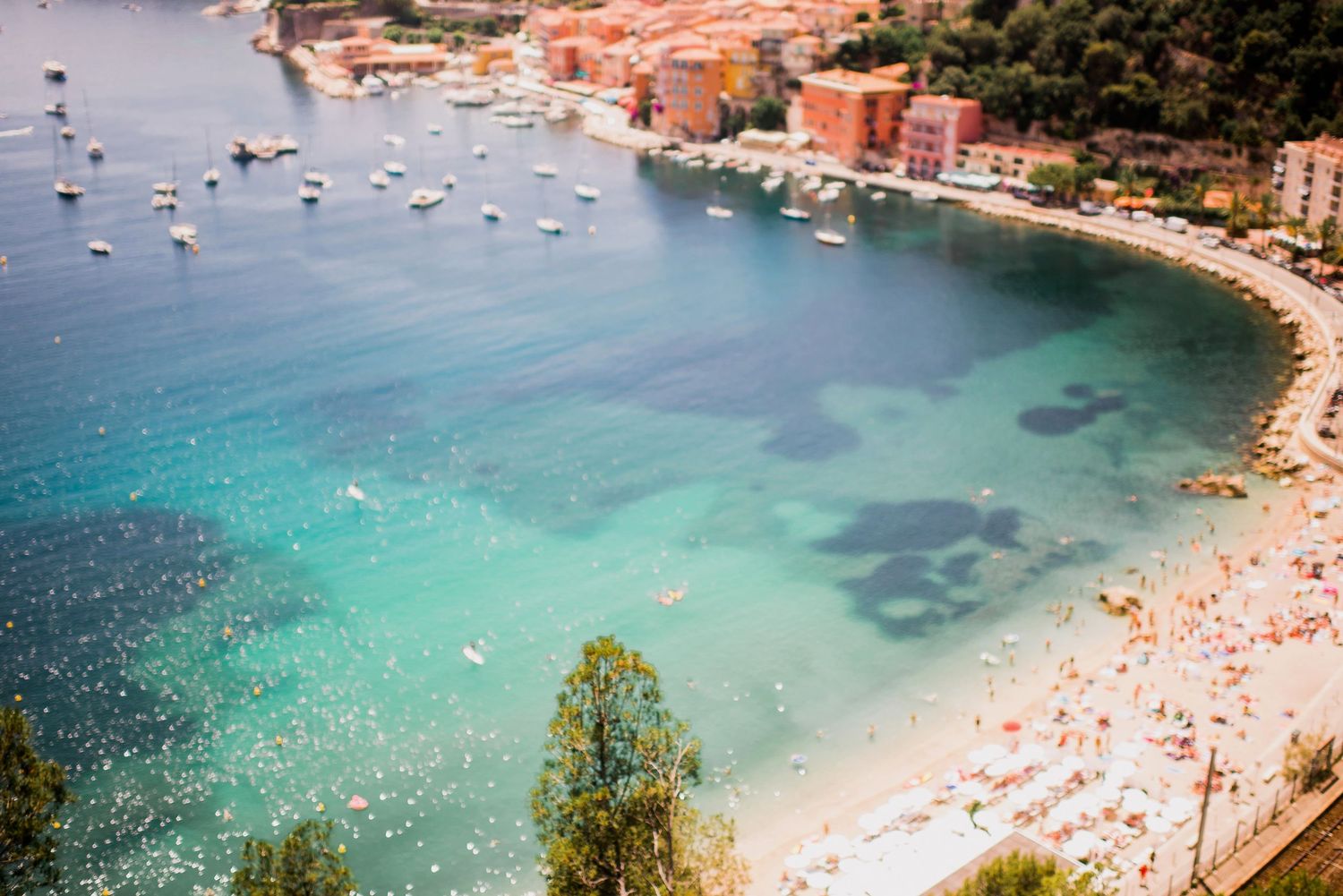Coastal beach town of beaulieu sur mer with crystal clear waters and boats anchored in the bay.