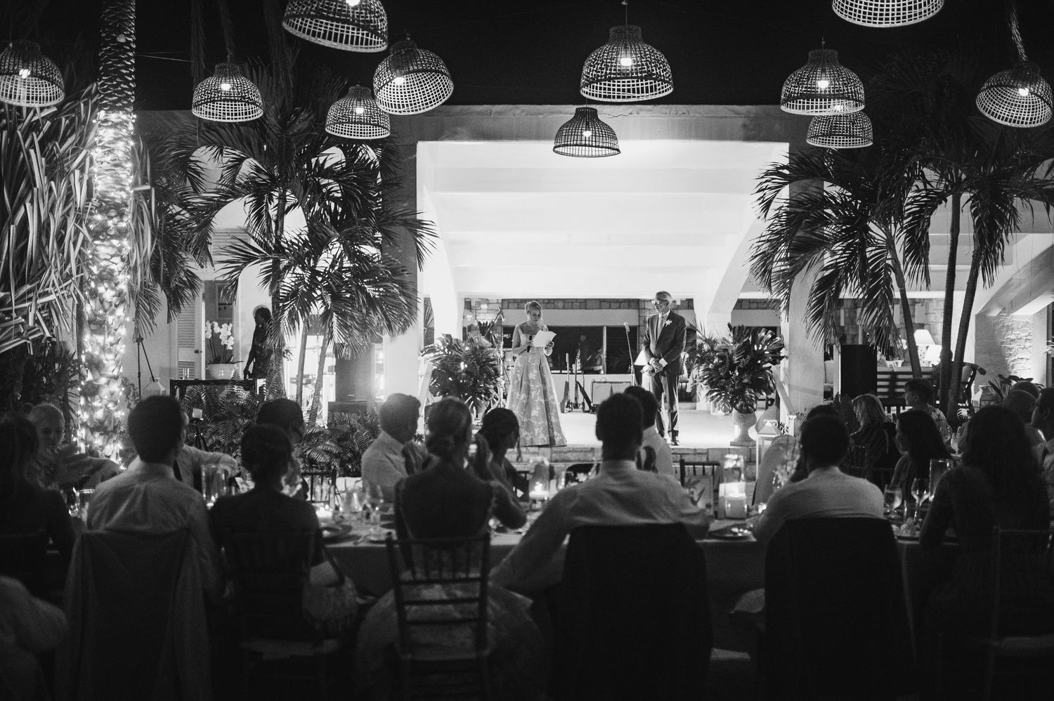 Black and white reception photos showing silhouettes of guests and hanging pendant lights.