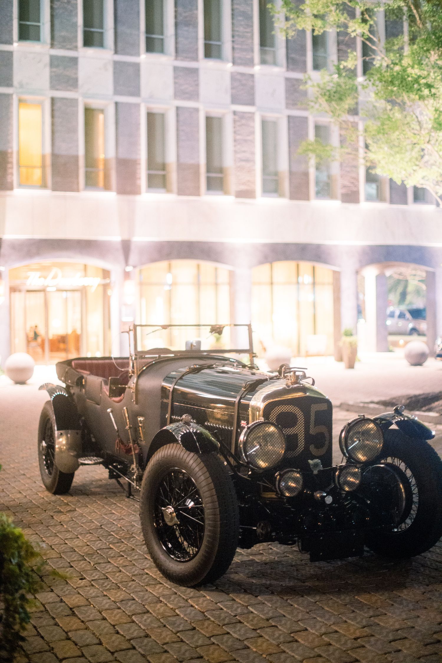 Classic vintage Bugatti racing cars parked in a row on a cobblestone street at dusk with warm lighting.