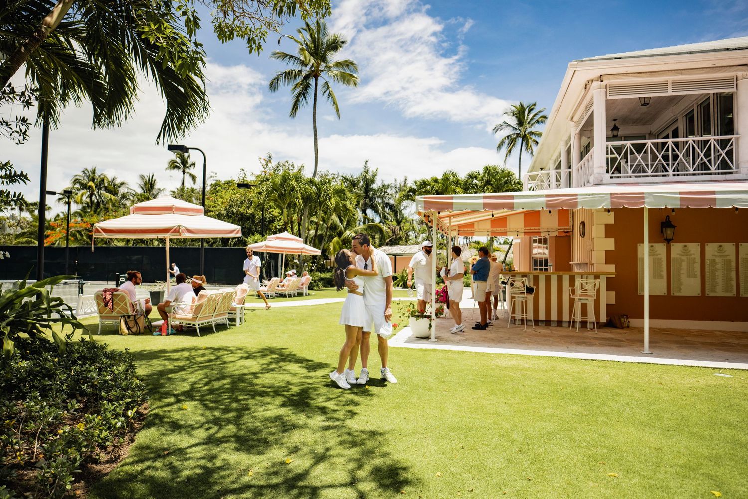Panoramic view of a lush green lawn with palm trees and white buildings at a tropical resort property.