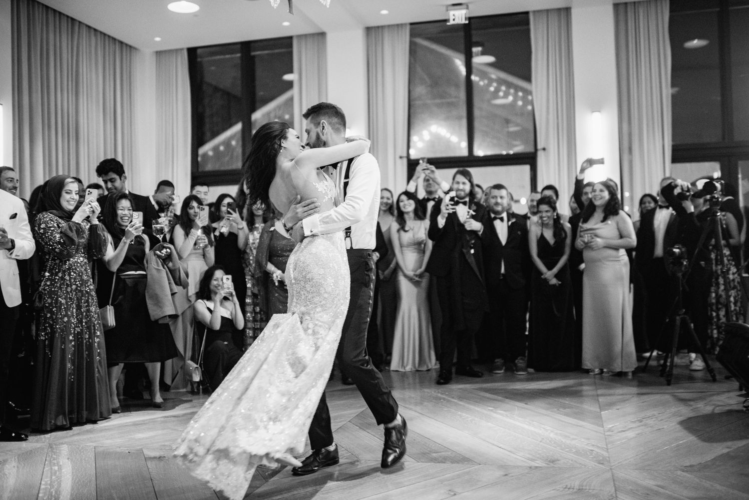 Black and white panoramic sequence of a wedding reception first dance with guests watching from the sides.