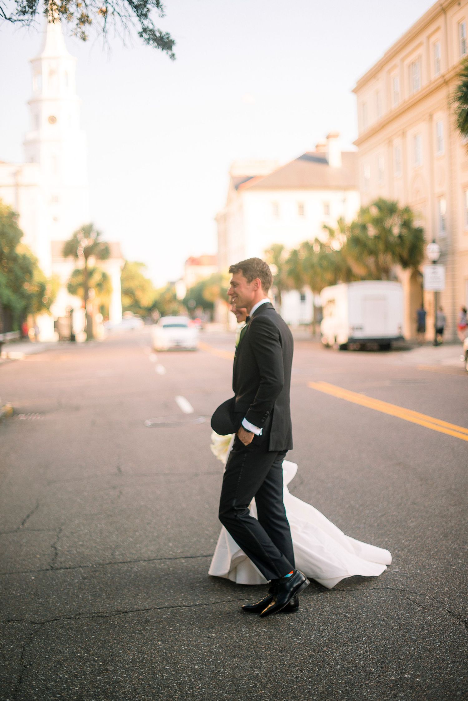 A couple in wedding attire shares a tender moment on a paved walkway at sunset.