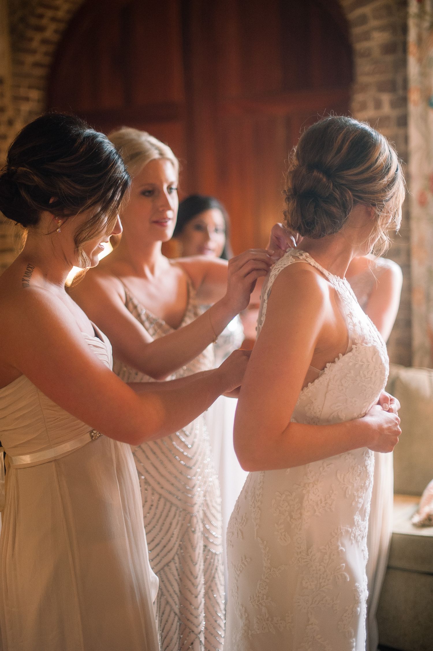 A series of candid moments showing women in white dresses embracing in warm lighting against a brick wall background.