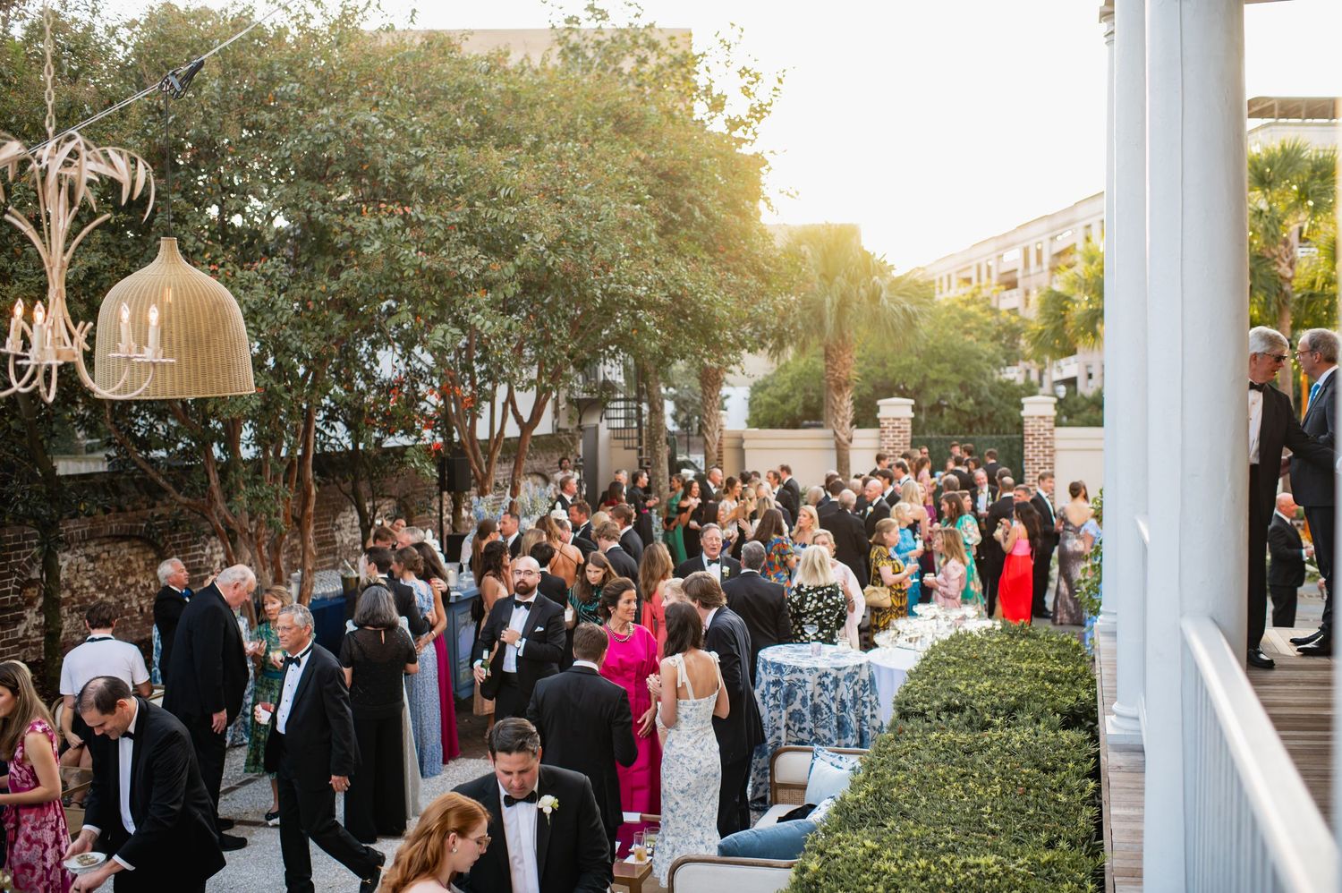 Wedding guests gather on a landscaped patio during an elegant outdoor reception at dusk.