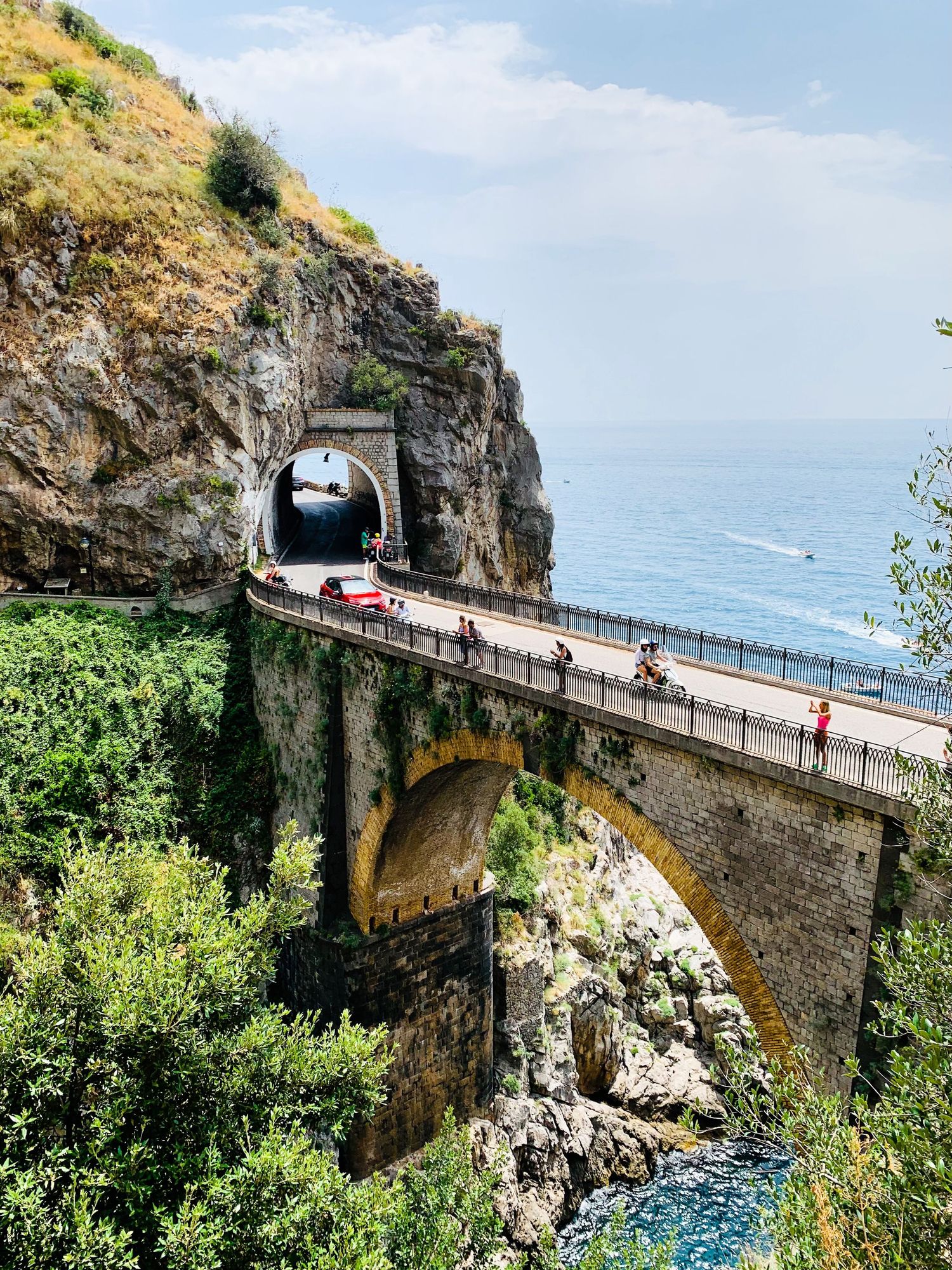 Historic stone arch bridge spans across a dramatic coastal gorge with ocean views.