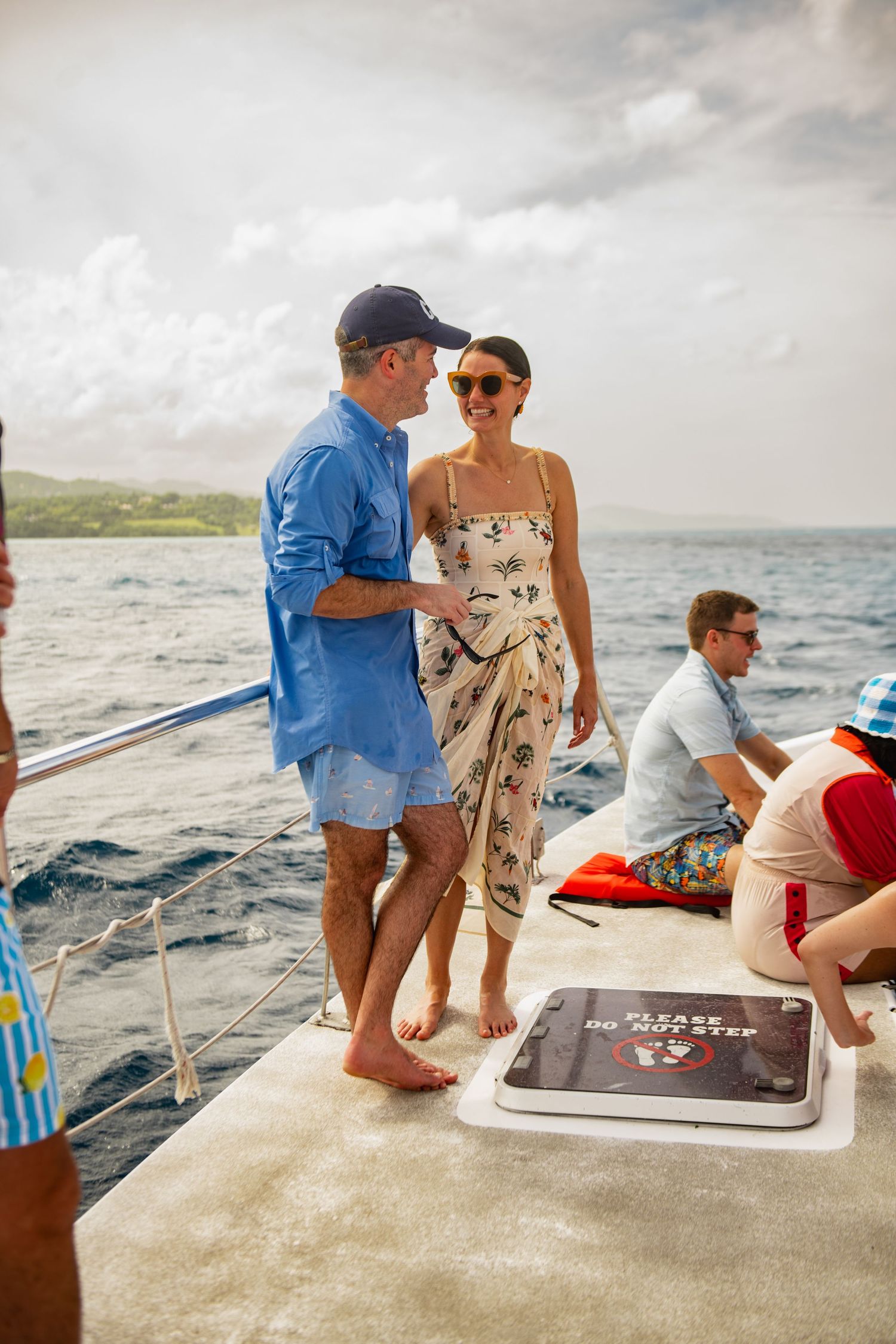 Group of people enjoying a scenic boat trip along a tropical coastline on a cloudy day.