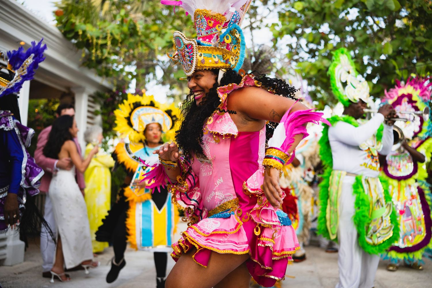 Colorful carnival parade featuring vibrant feathered costumes and masks in bright tropical colors.