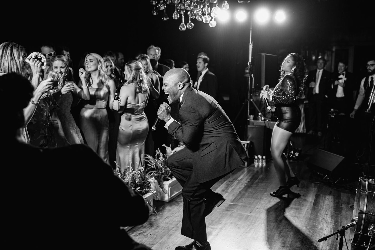 People dancing and celebrating at a lively wedding reception party under dimmed lights.