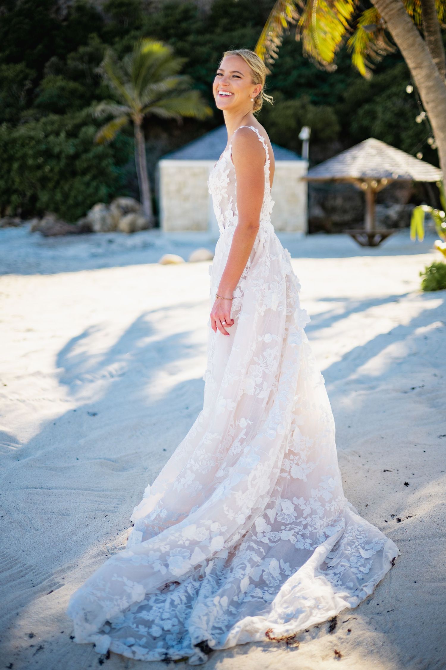 White lace wedding dress flowing in the breeze on a tropical beach.
