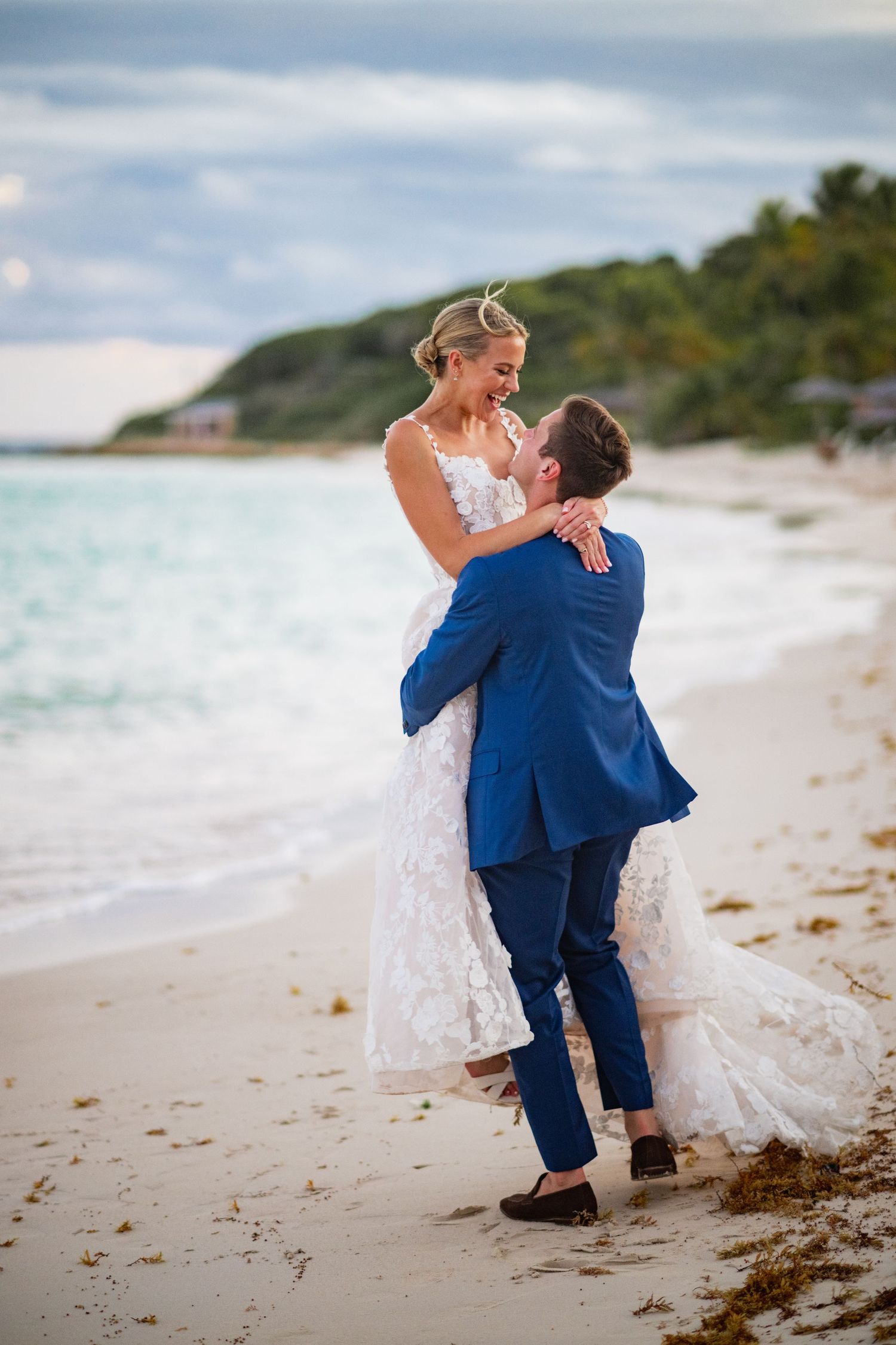 Newlyweds share intimate moments on a pristine beach with white sand and turquoise waters.