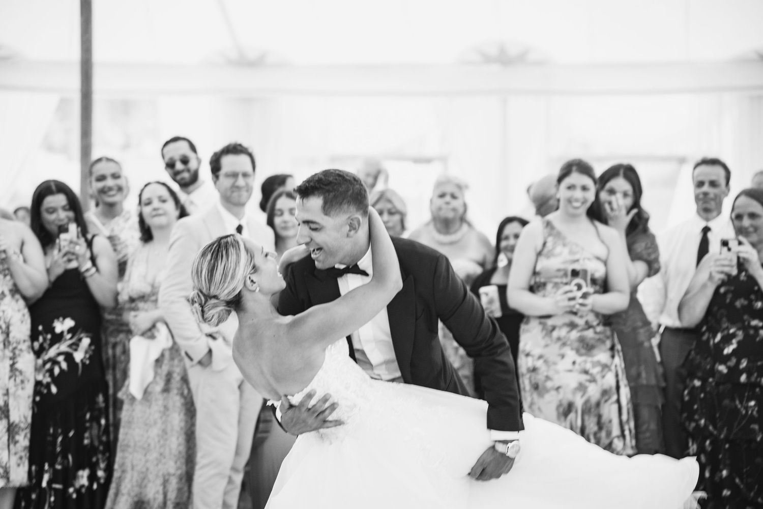 Black and white photo of wedding guests celebrating with confetti and joyful expressions.