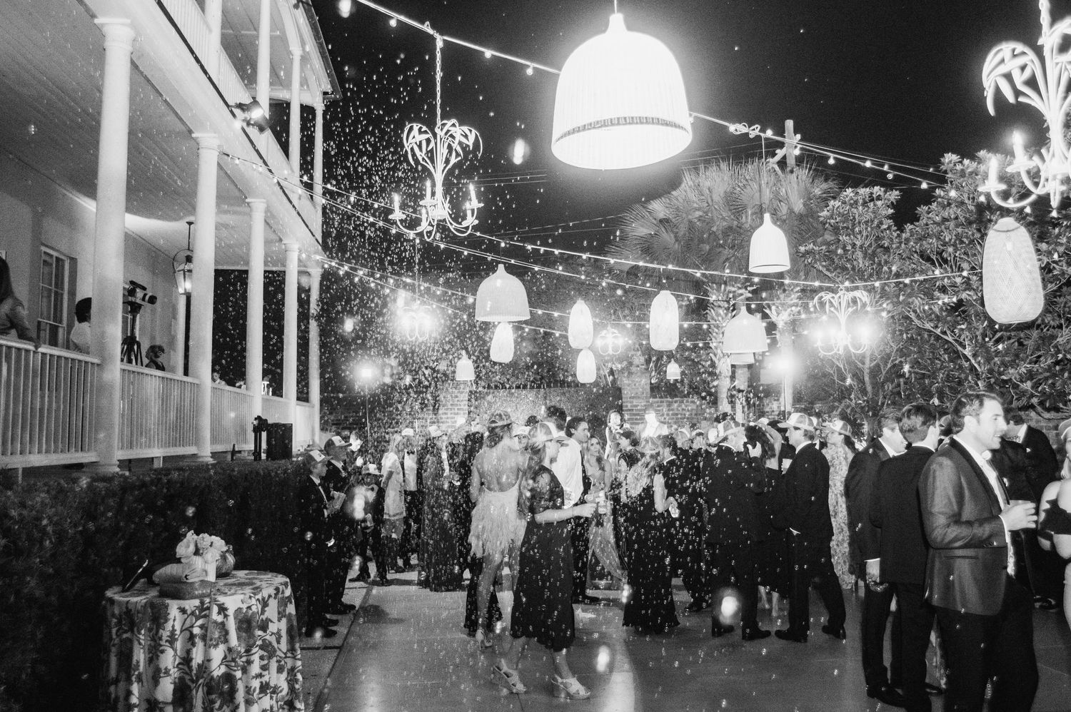 Vintage black and white photograph showing illuminated street lamps and crowds gathering along Main Street USA at Disneyland.